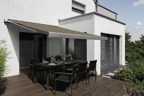 Ausgefahrene Markise über einer Terrasse mit Essplatz an einem modernen Wohnhaus